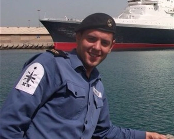 Michael Knights, in uniform. Large ship in background.